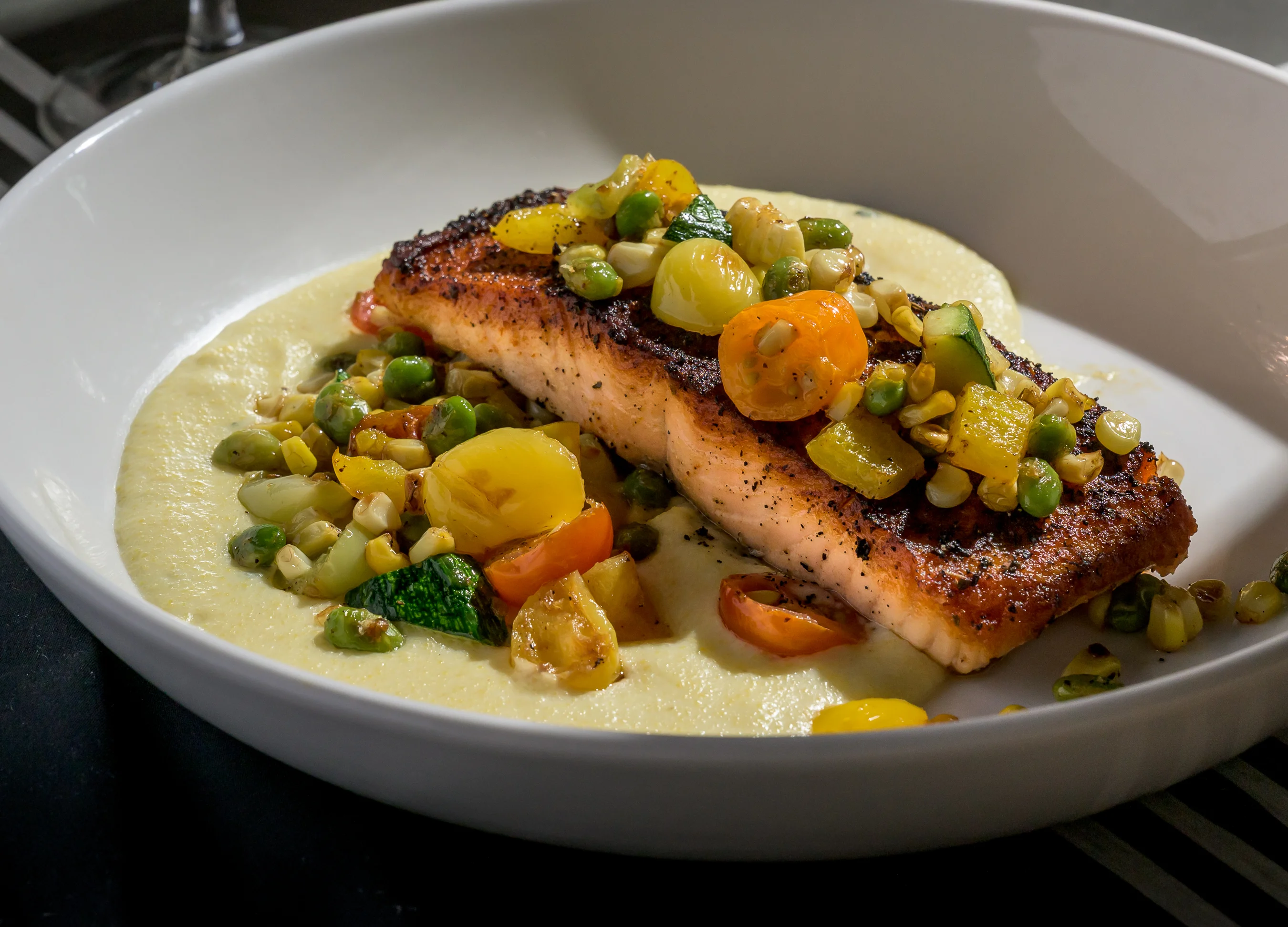 Grilled salmon with creamy grits and seasonal vegetables