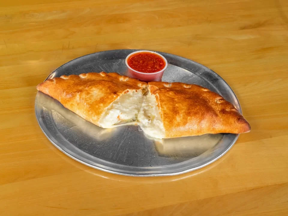 Cheesy calzone served with marinara sauce