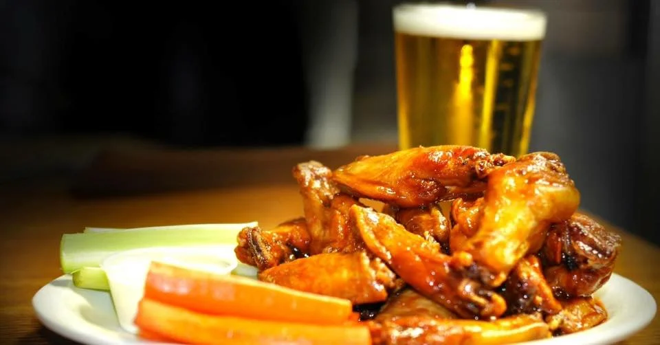 Buffalo chicken wings with celery, carrots, and beer