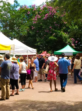 Vibrant farmers market with colorful tents and visitors