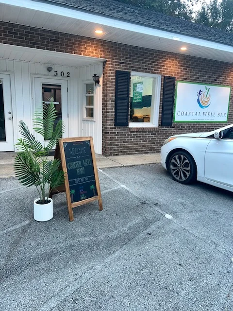 Exterior view of Coastal Well Bar with welcoming sign and greenery