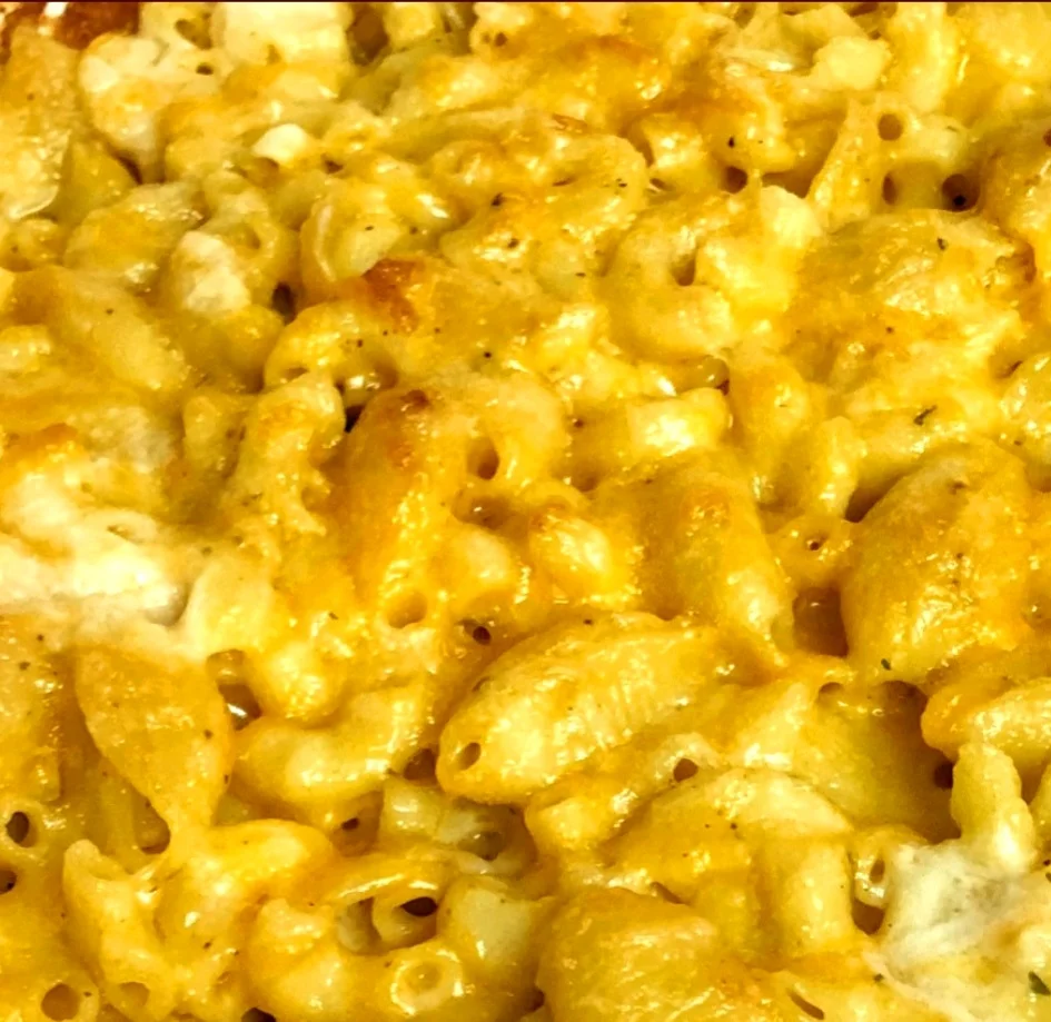 A close-up of creamy macaroni and cheese, featuring a golden topping and perfectly cooked pasta shells.
