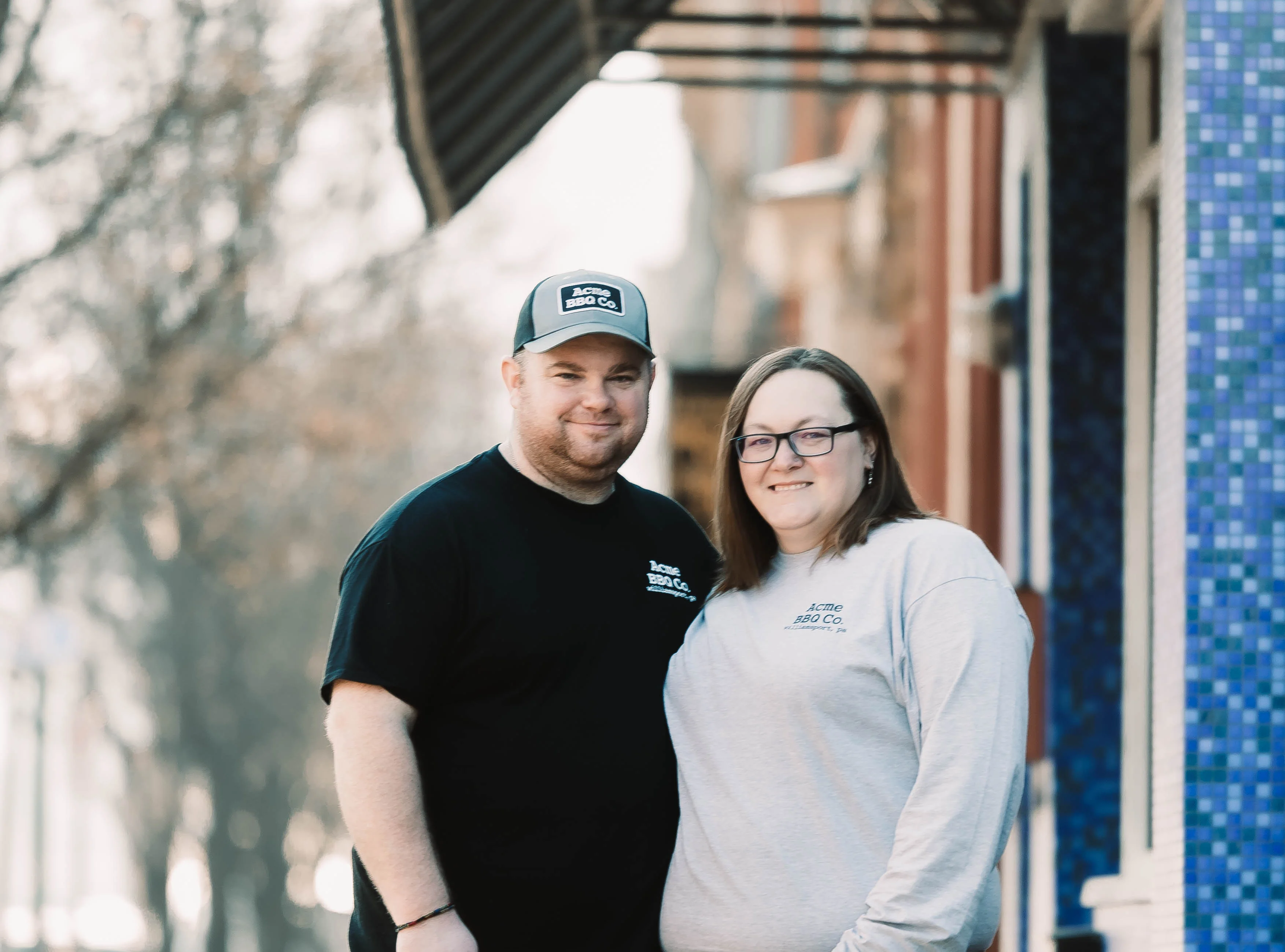 Couple posing outside Acme BBQ Co. restaurant