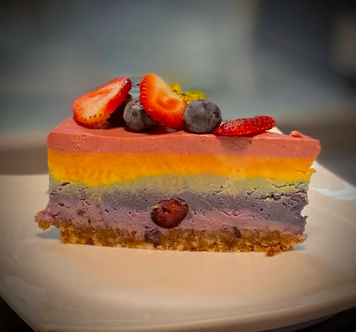 Layered berry mousse cake topped with fresh strawberries and blueberries