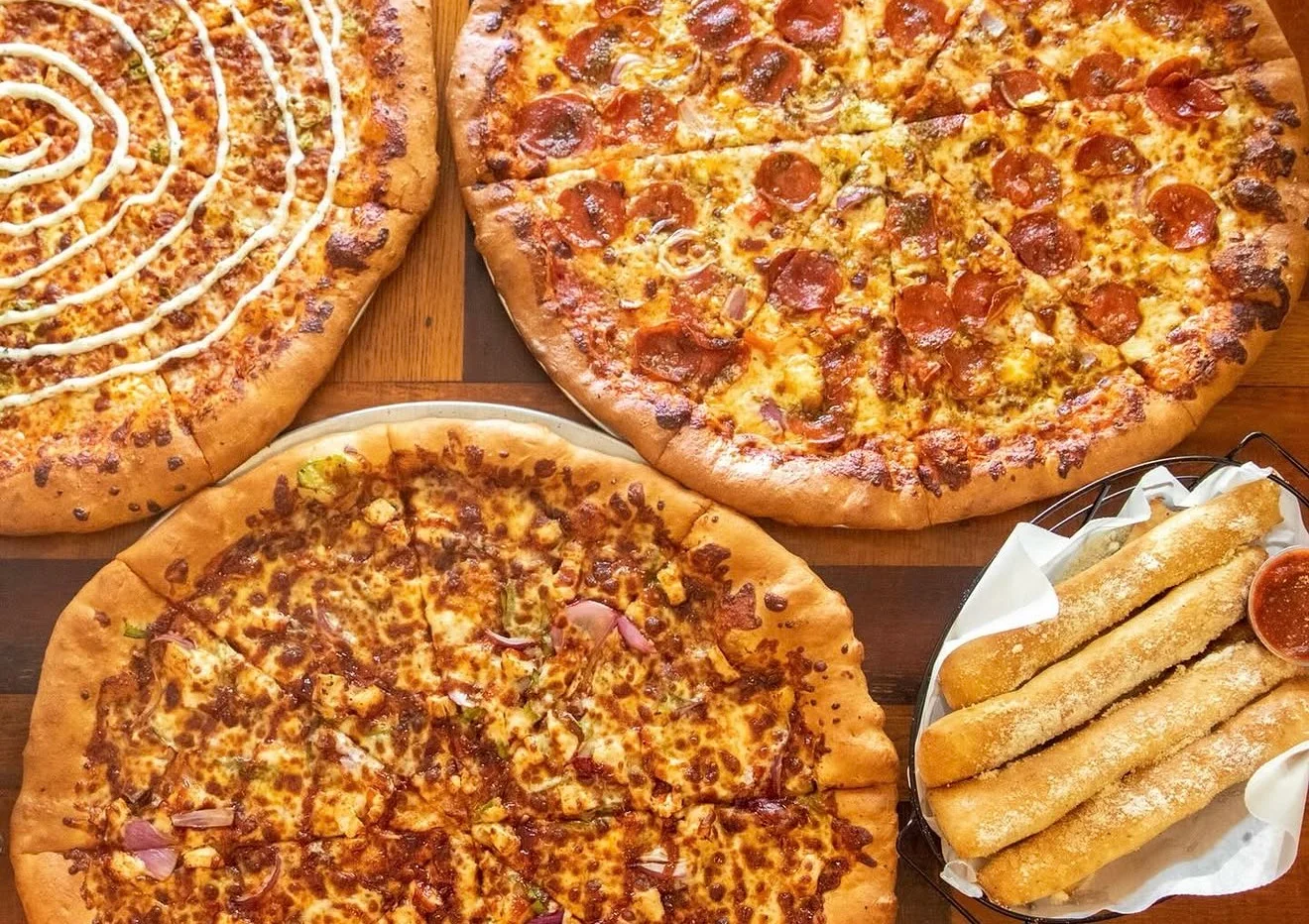 Assorted pizzas including pepperoni and cheesy breadsticks