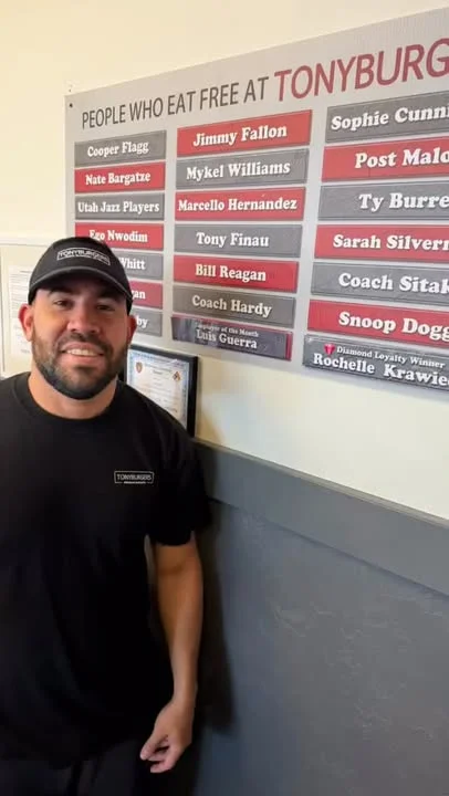 Person posing next to a restaurant wall of fame at Tonyburg