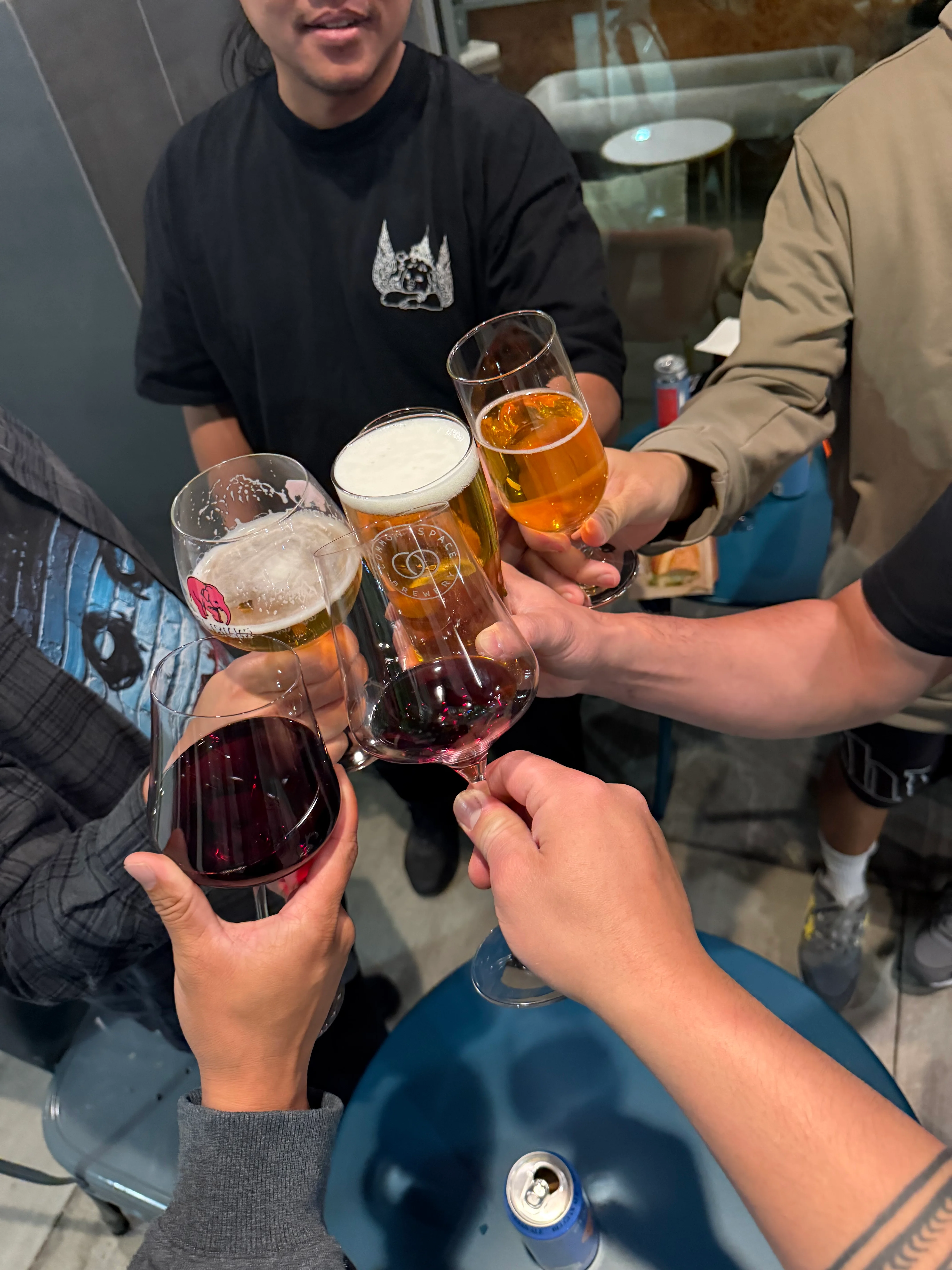 Group of friends toasting with various drinks at a restaurant.