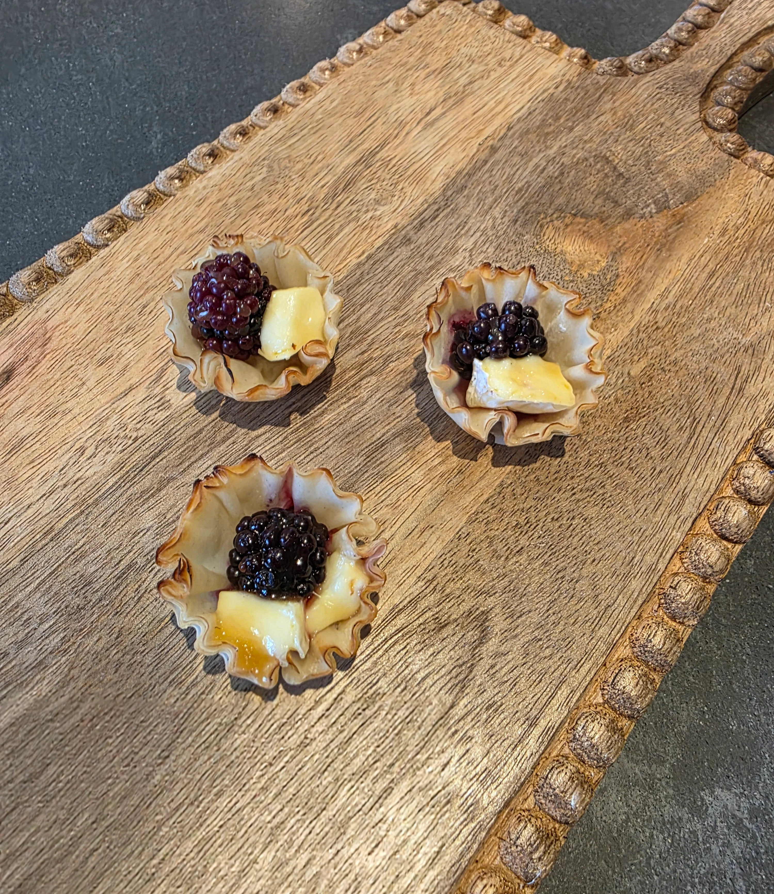 Miniature blackberry tartlets on a wooden platter