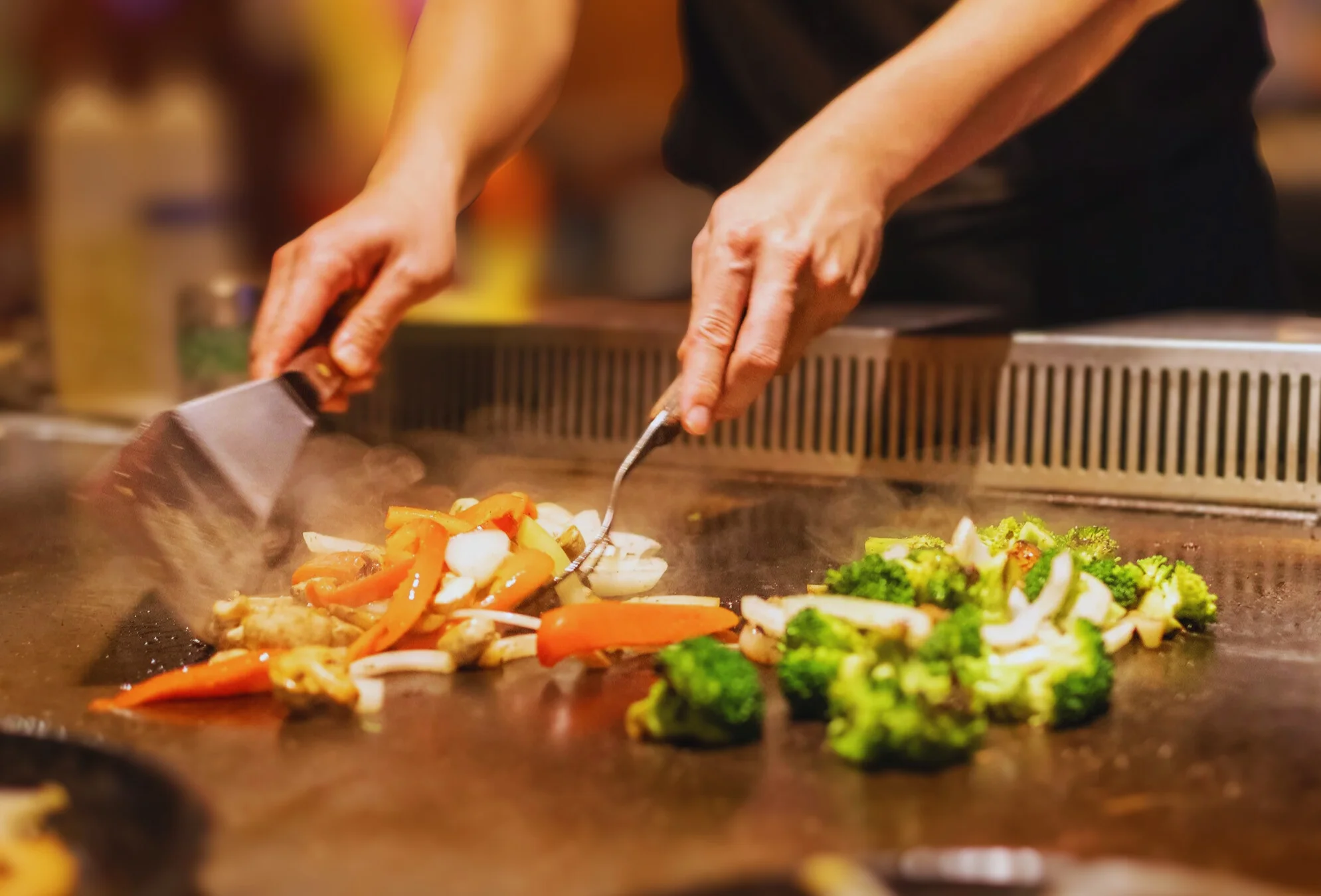 Teppanyaki chef grilling fresh vegetables