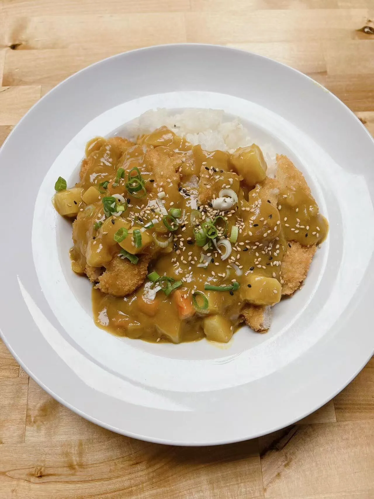 Japanese katsu curry served over rice with green onions and sesame seeds
