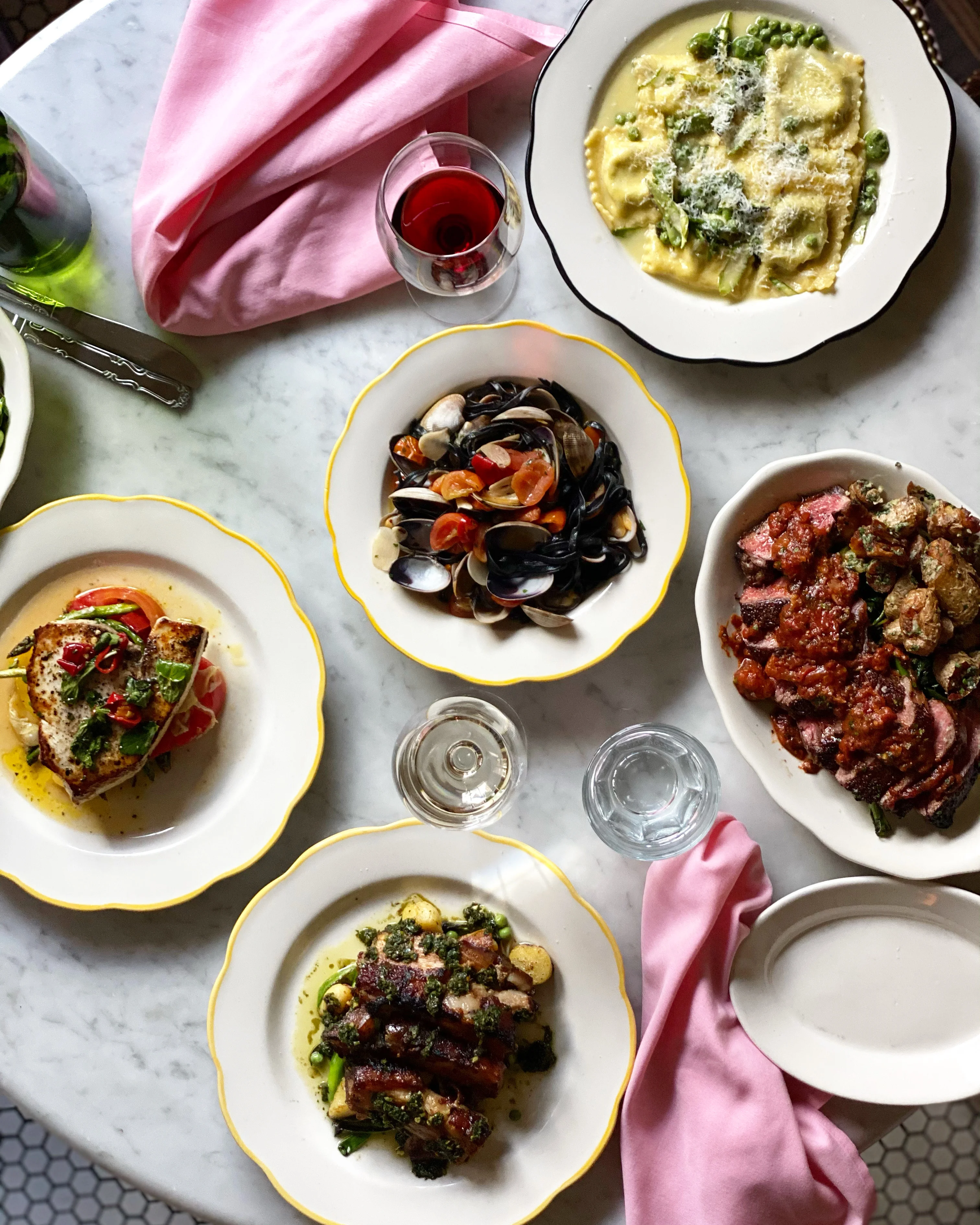 Italian seafood pasta and grilled meats on a marble table