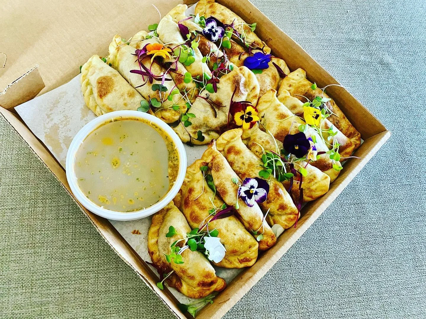 Golden empanadas with edible flowers and dipping sauce