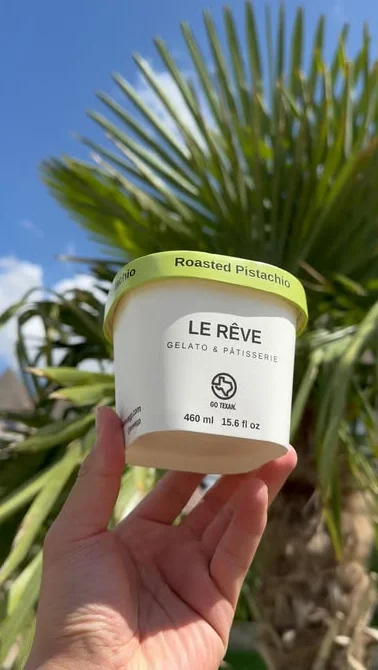 Container of roasted pistachio gelato under a palm tree