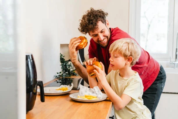 Father and son enjoying homemade burgers in a cozy kitchen