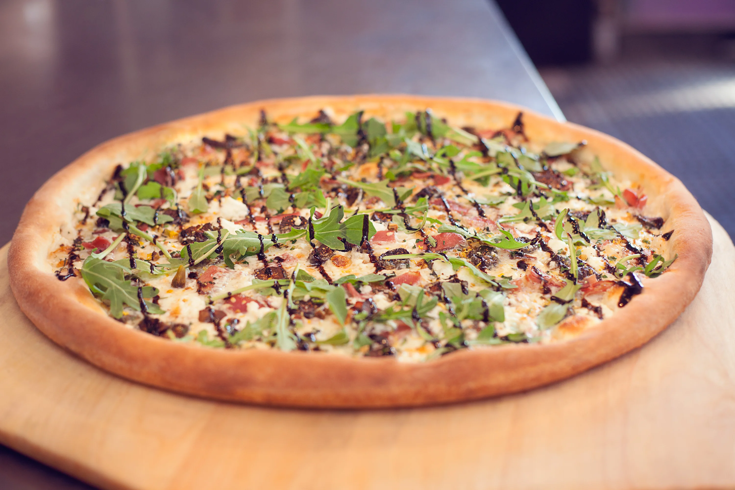 Gourmet pizza topped with fresh arugula and balsamic drizzle