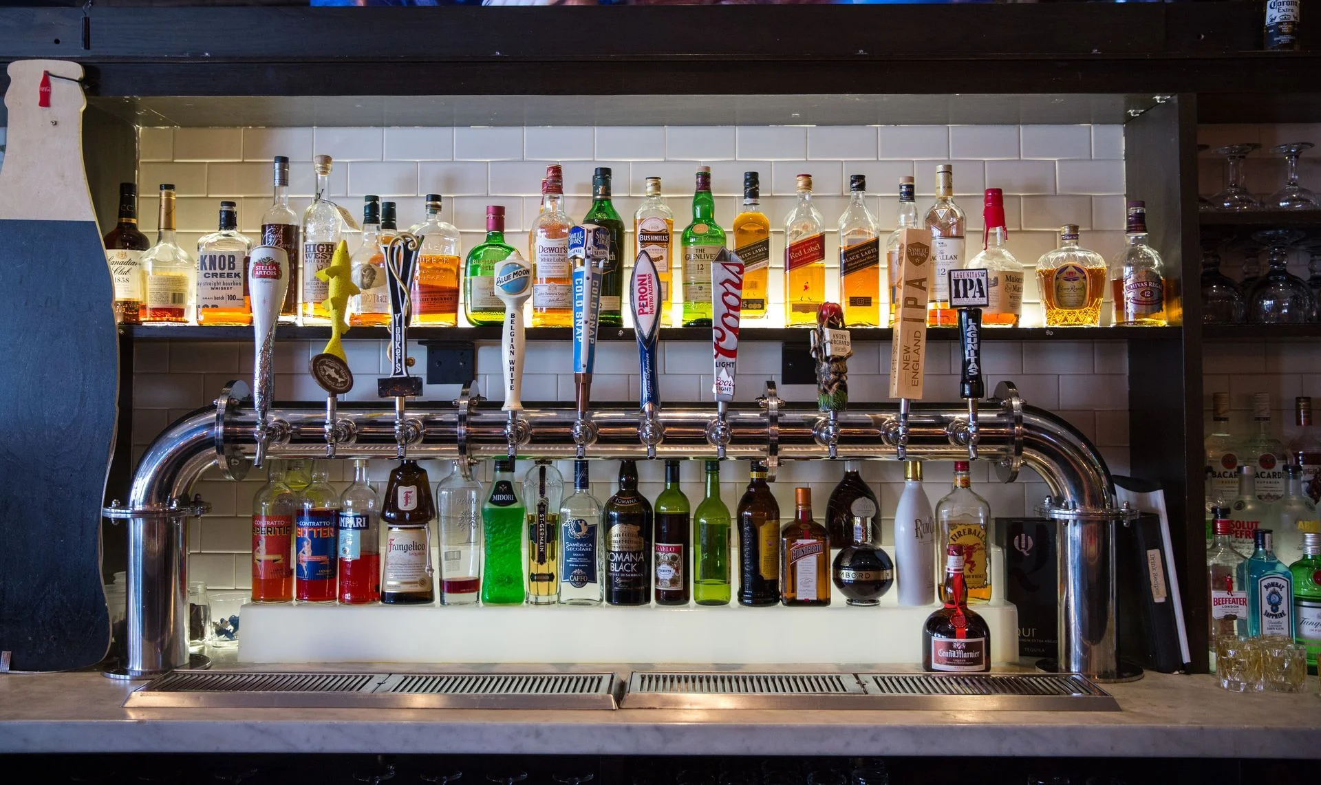 Well-stocked bar with various liquor bottles and draft beer taps