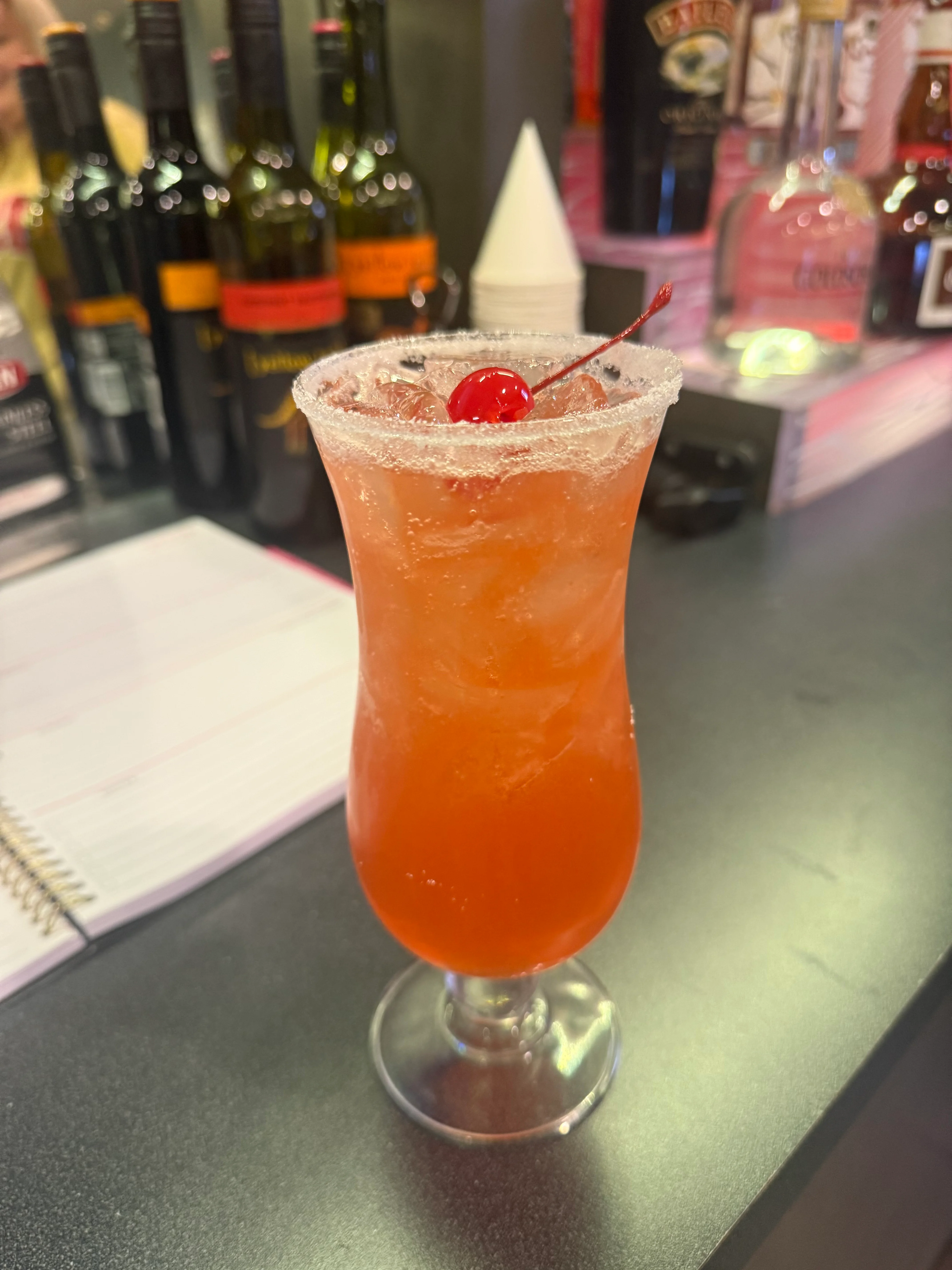 Colorful cocktail garnished with a cherry at a modern bar