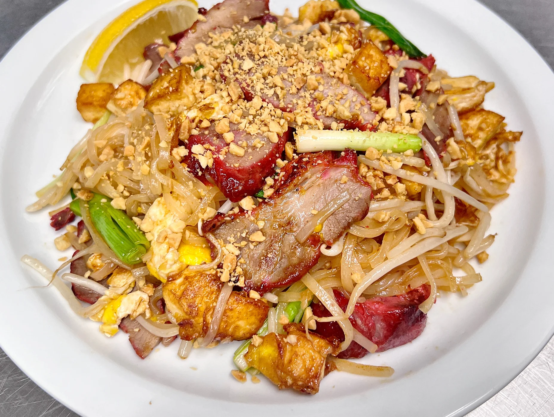 Plate of Thai pad see ew with grilled pork and crushed peanuts