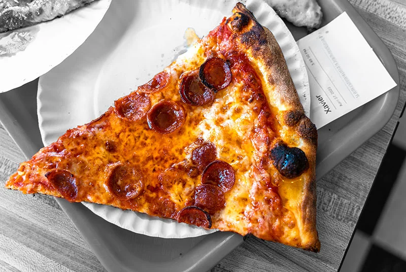 Slice of pepperoni pizza on a paper plate