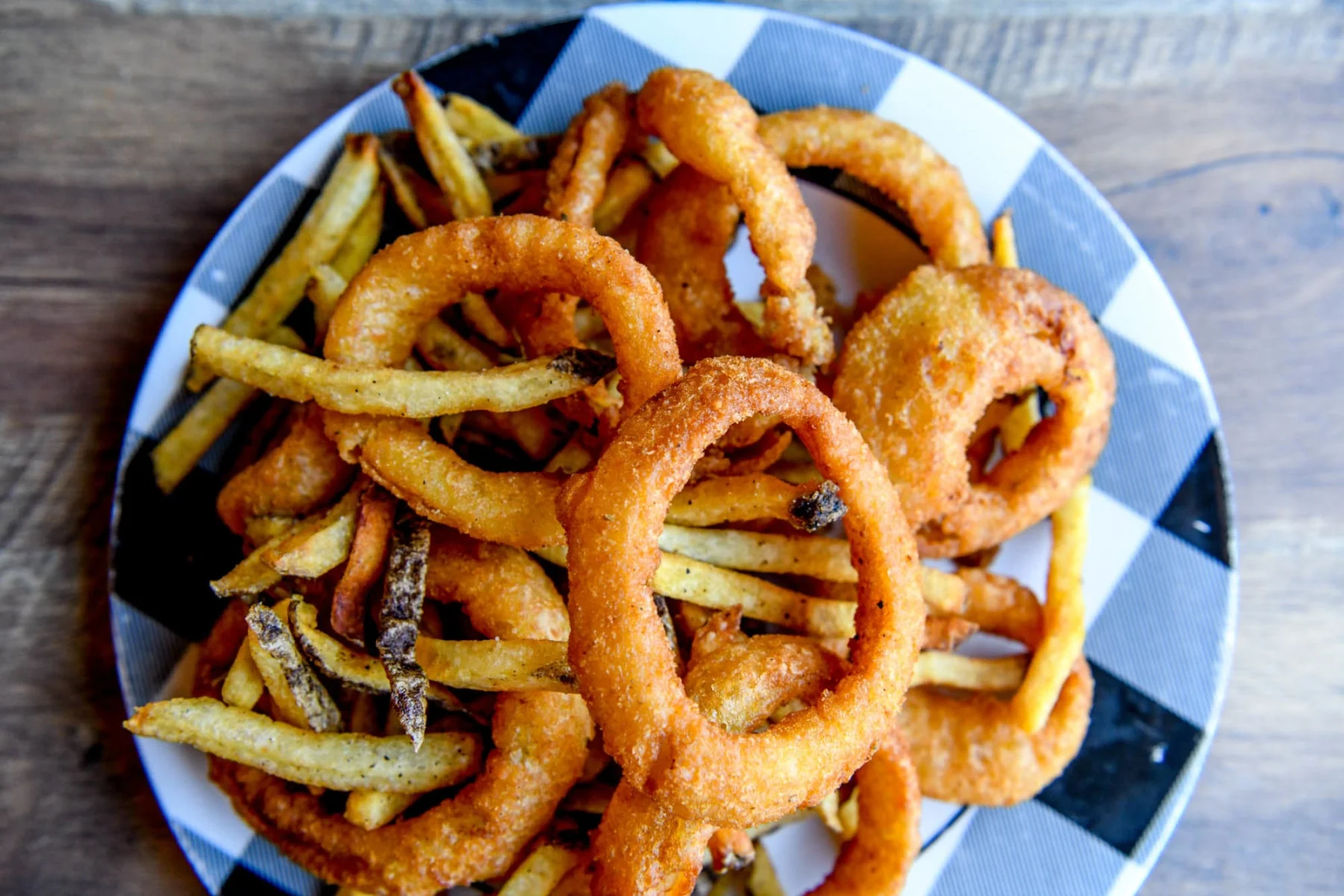 Crispy onion rings and French fries on a checkered plate