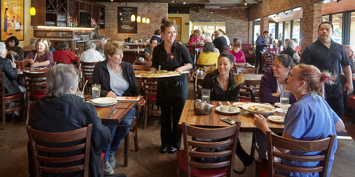A server dropping off pizza to customers