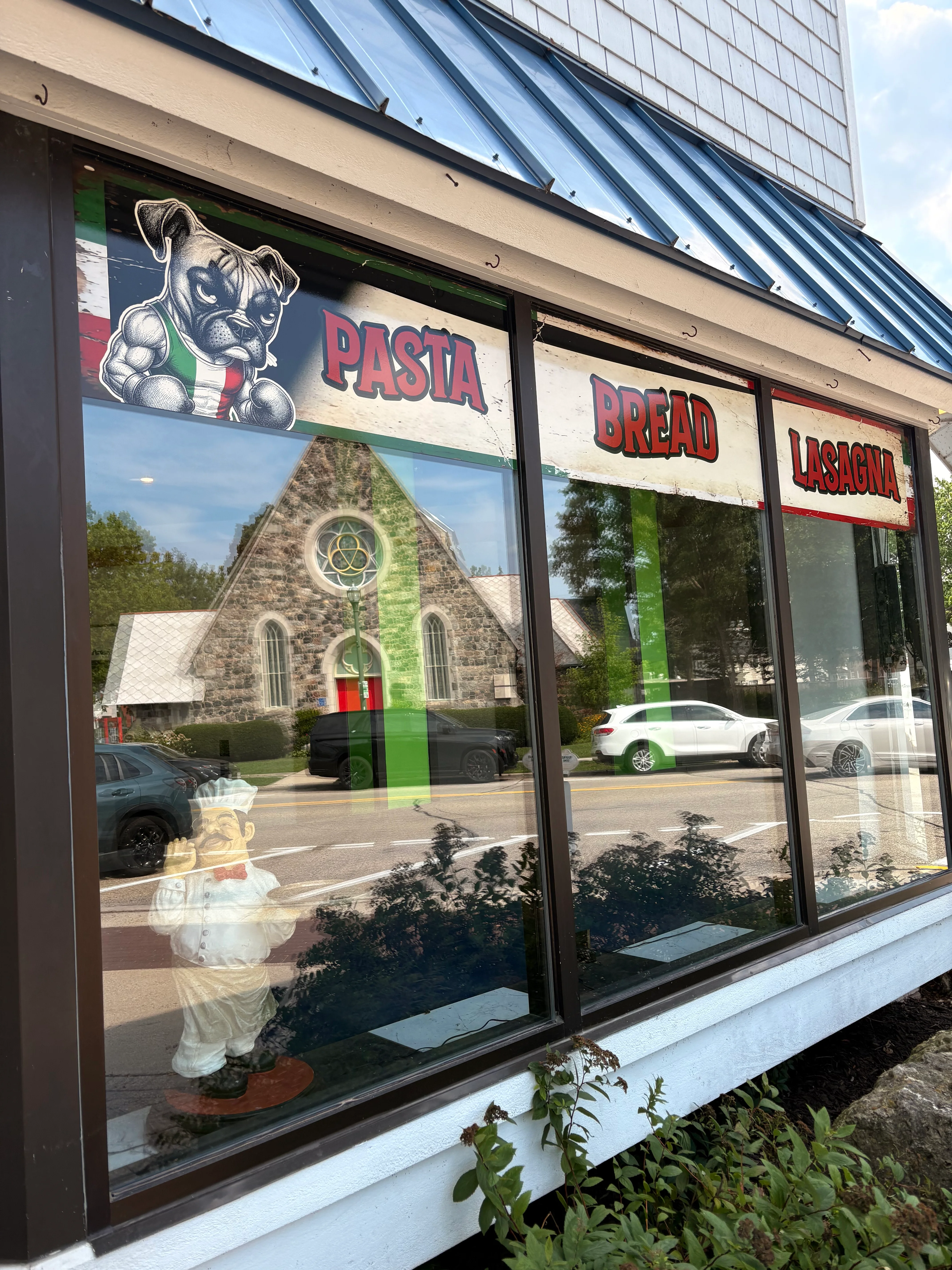 Restaurant window showcasing Italian cuisine with pasta and lasagna signs