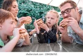Family enjoying burgers at an outdoor table