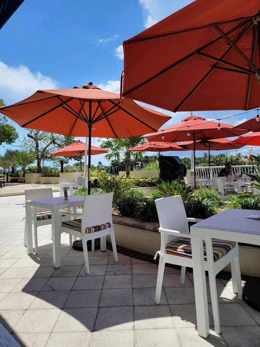 Outdoor dining area with red umbrellas and white furniture
