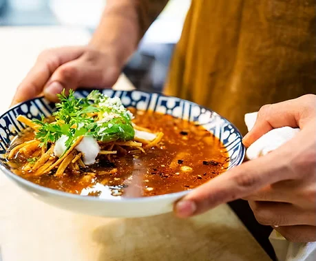 Spicy Sichuan noodle soup garnished with fresh herbs
