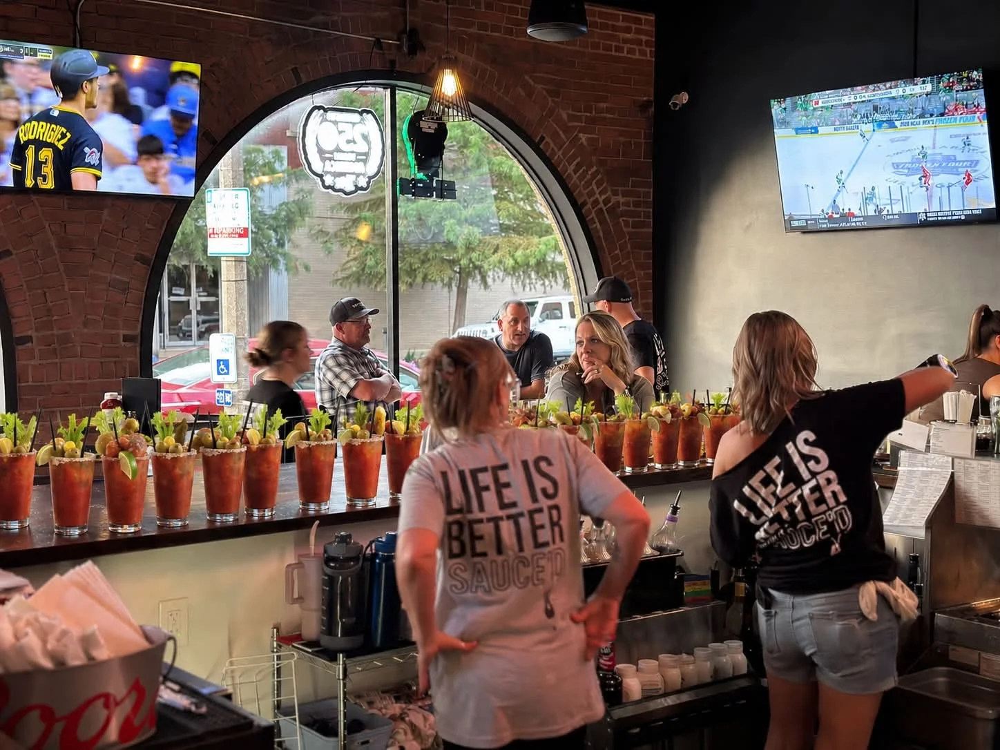 Bartender preparing Bloody Mary cocktails at a lively bar