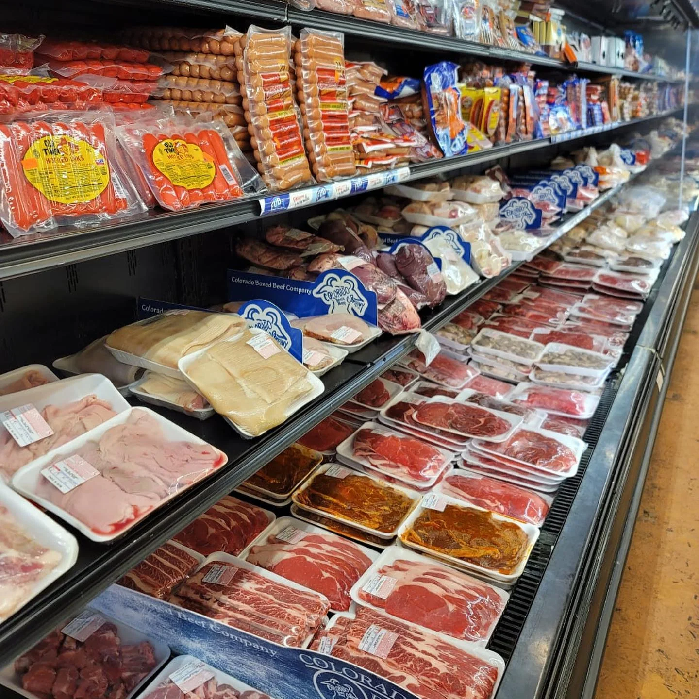 Variety of meats displayed in a grocery store cooler