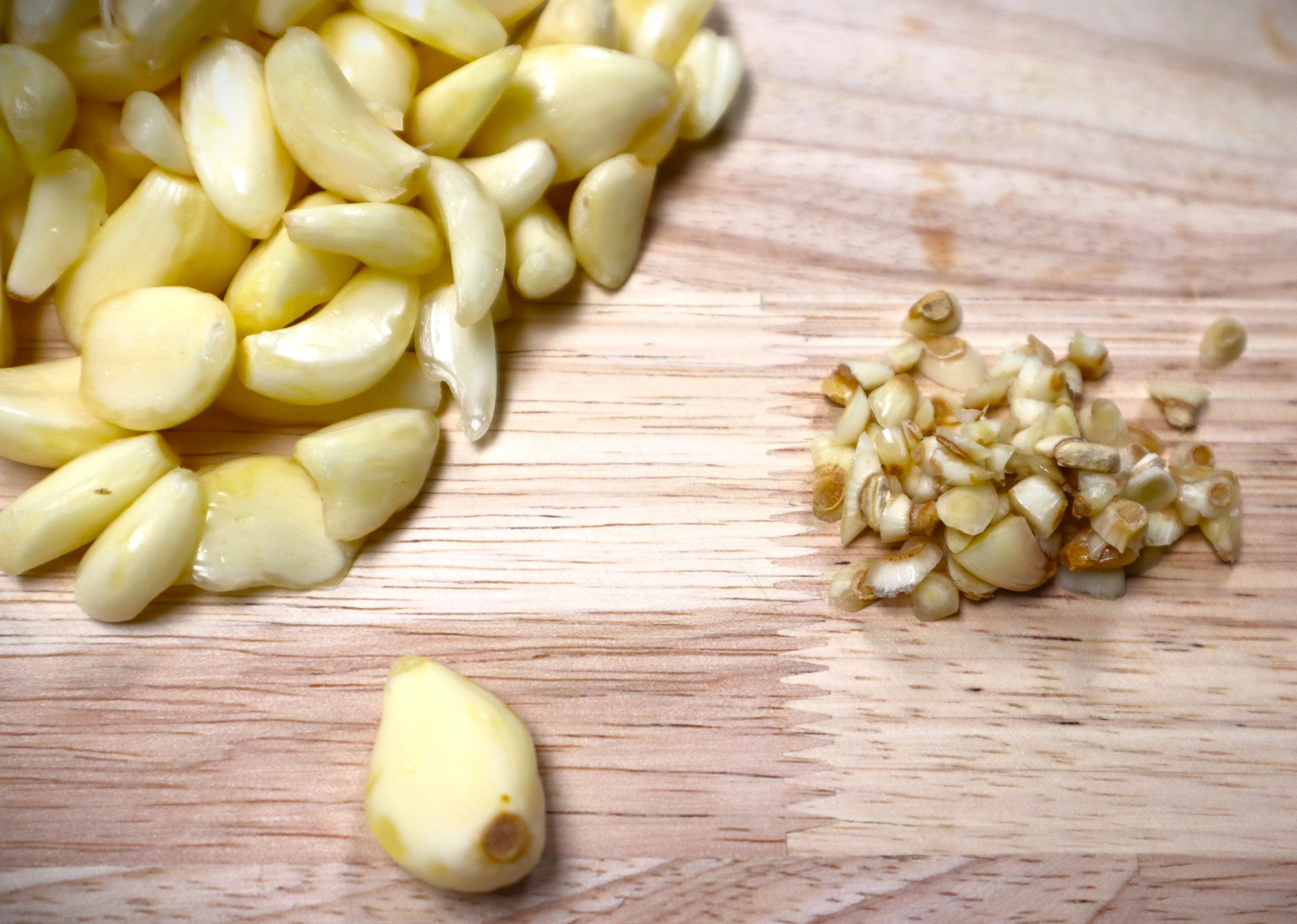 Freshly peeled garlic cloves on a wooden cutting board