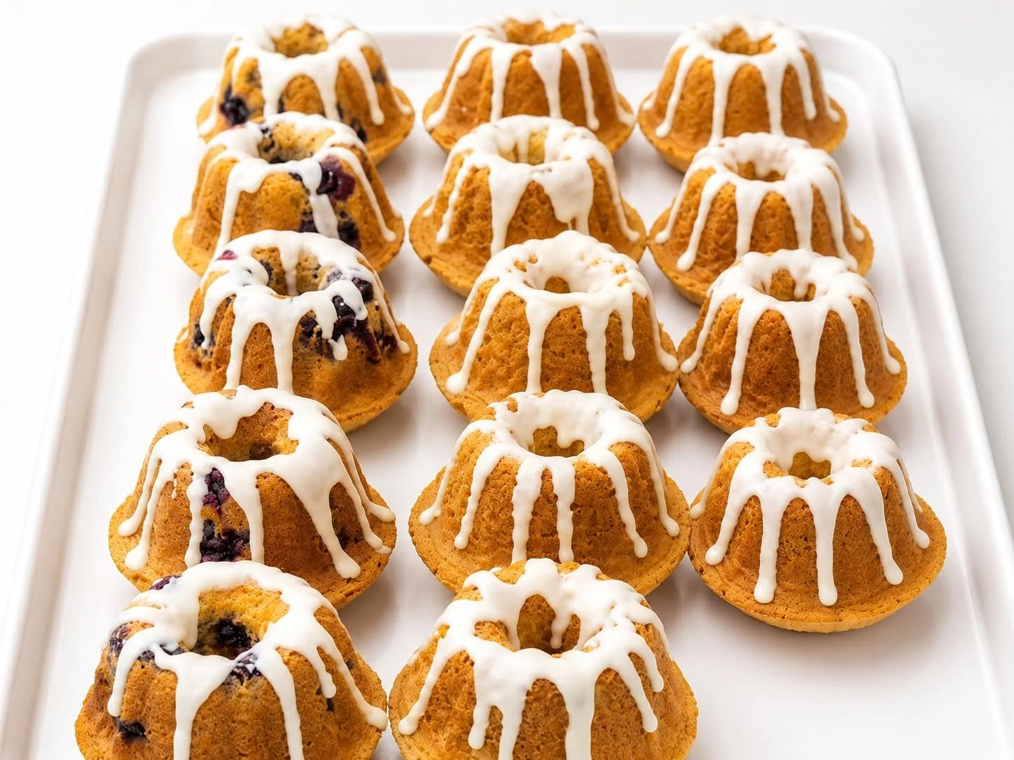 Mini bundt cakes drizzled with icing on a white platter