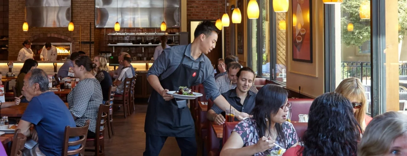 Server delivering food to a guest and holding a Beet Salad