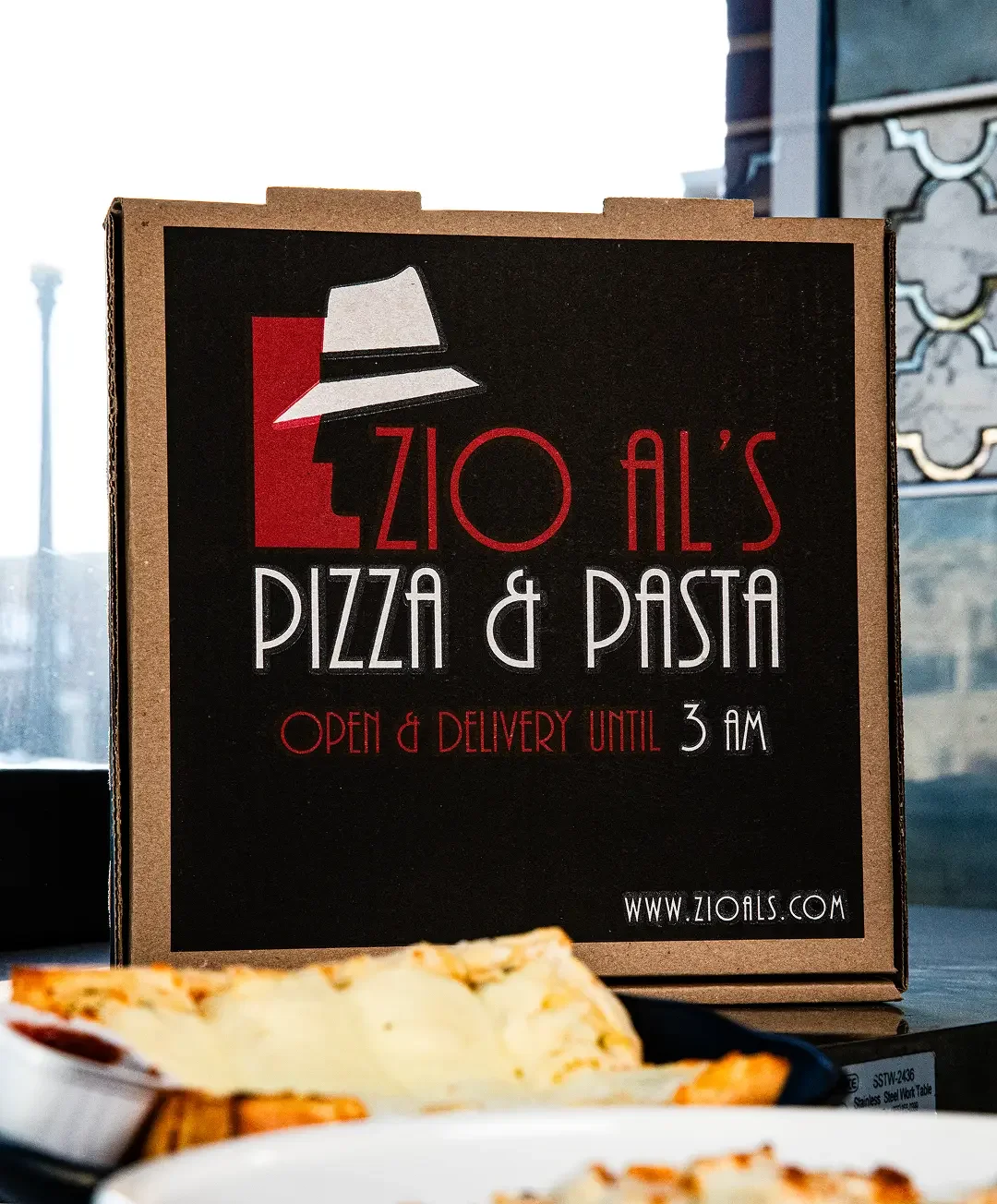 Zio Al's Pizza & Pasta delivery box with food items on a table.