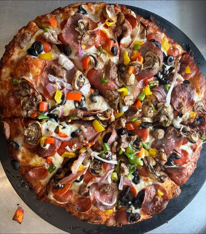 A large pizza topped with various ingredients including pepperoni, mushrooms, and bell peppers, showcasing a colorful assortment.
