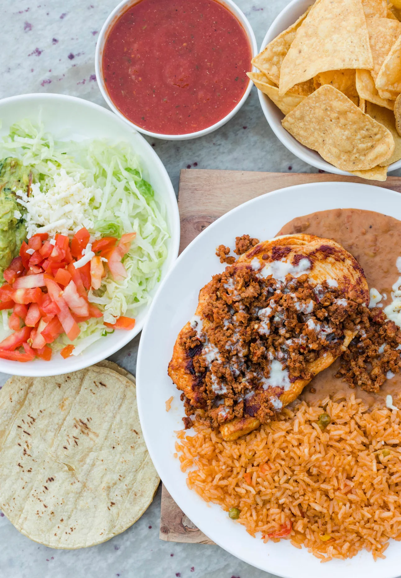 Mexican plate with enchiladas, rice, beans, and fresh toppings