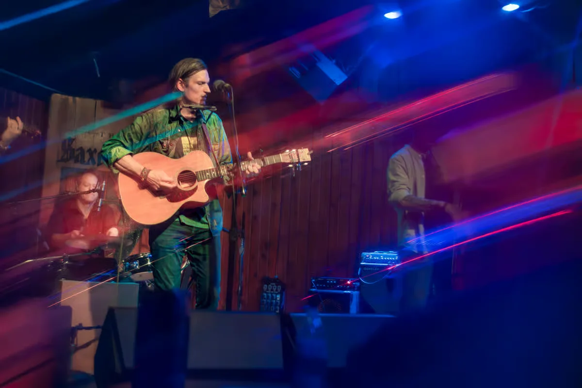 Live music performance with guitarist on stage and colorful lighting effects