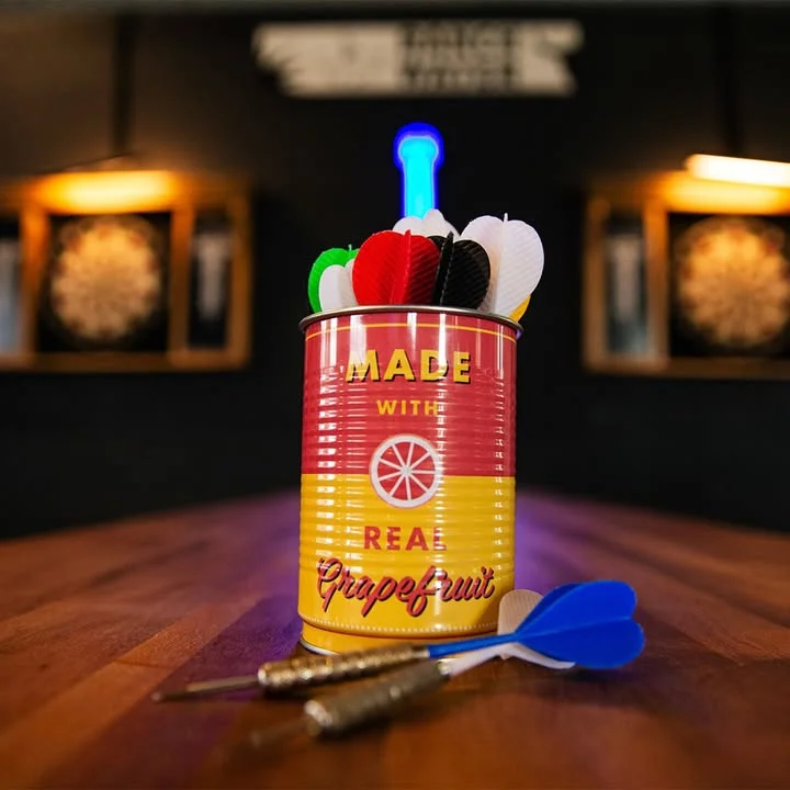 Colorful dartboard setup with darts in a vintage can on a wooden table