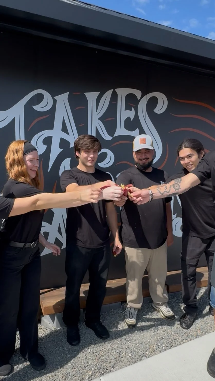 Restaurant staff celebrating with drinks in front of a mural