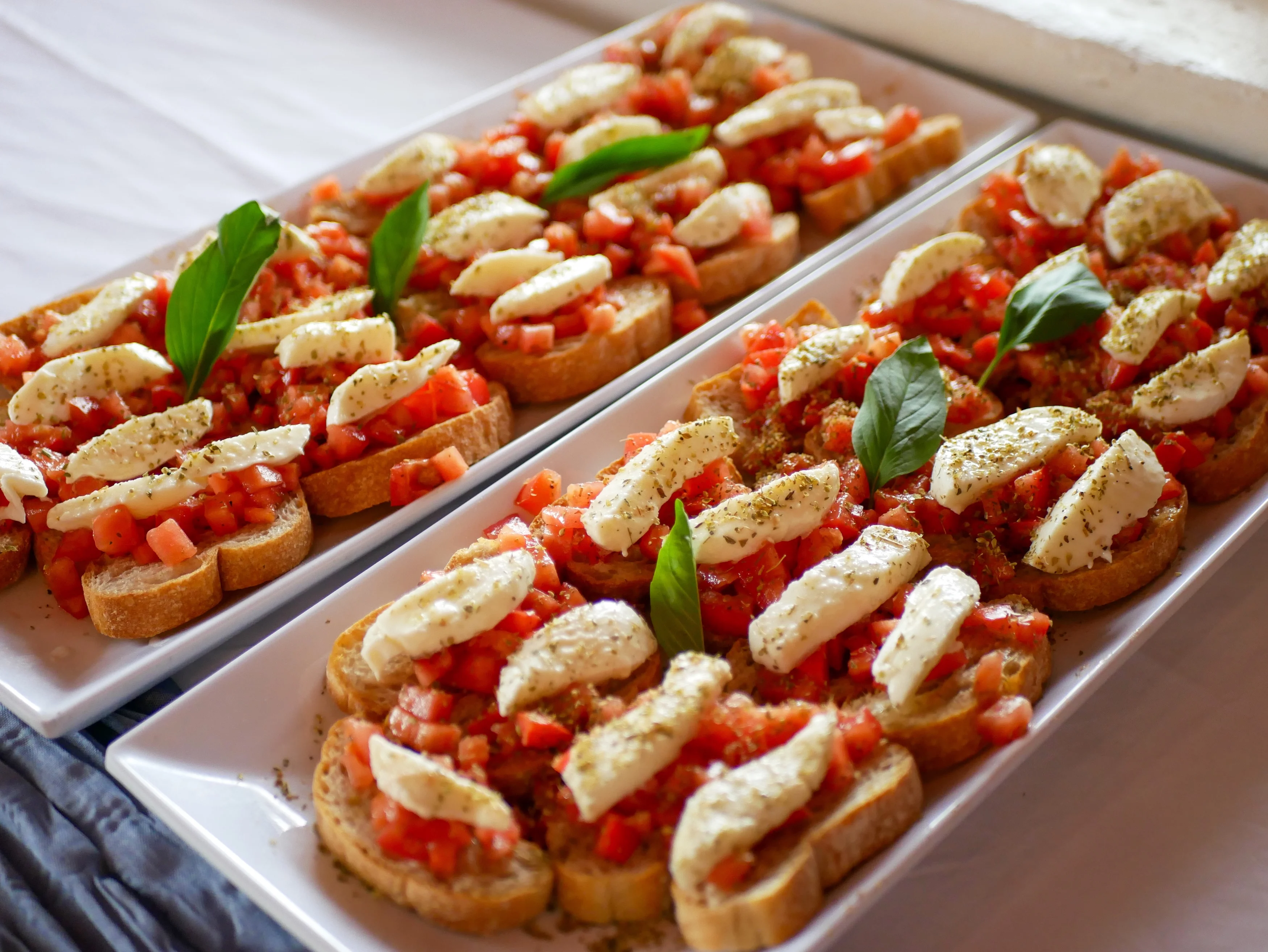 A platter of bruschetta topped with fresh tomatoes, mozzarella cheese, and basil leaves, beautifully arranged for serving.