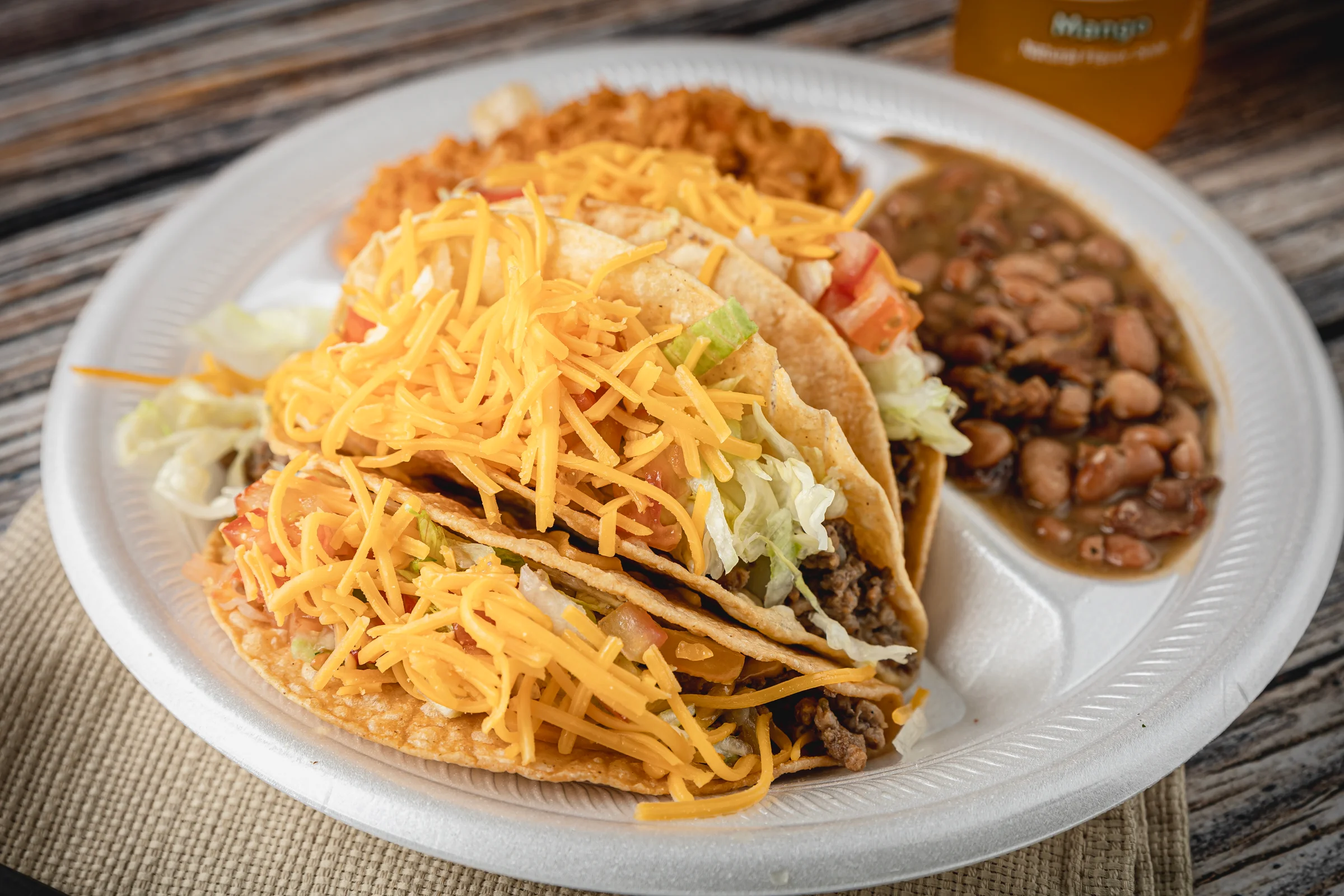 A taco platter with a side of beans and rice
