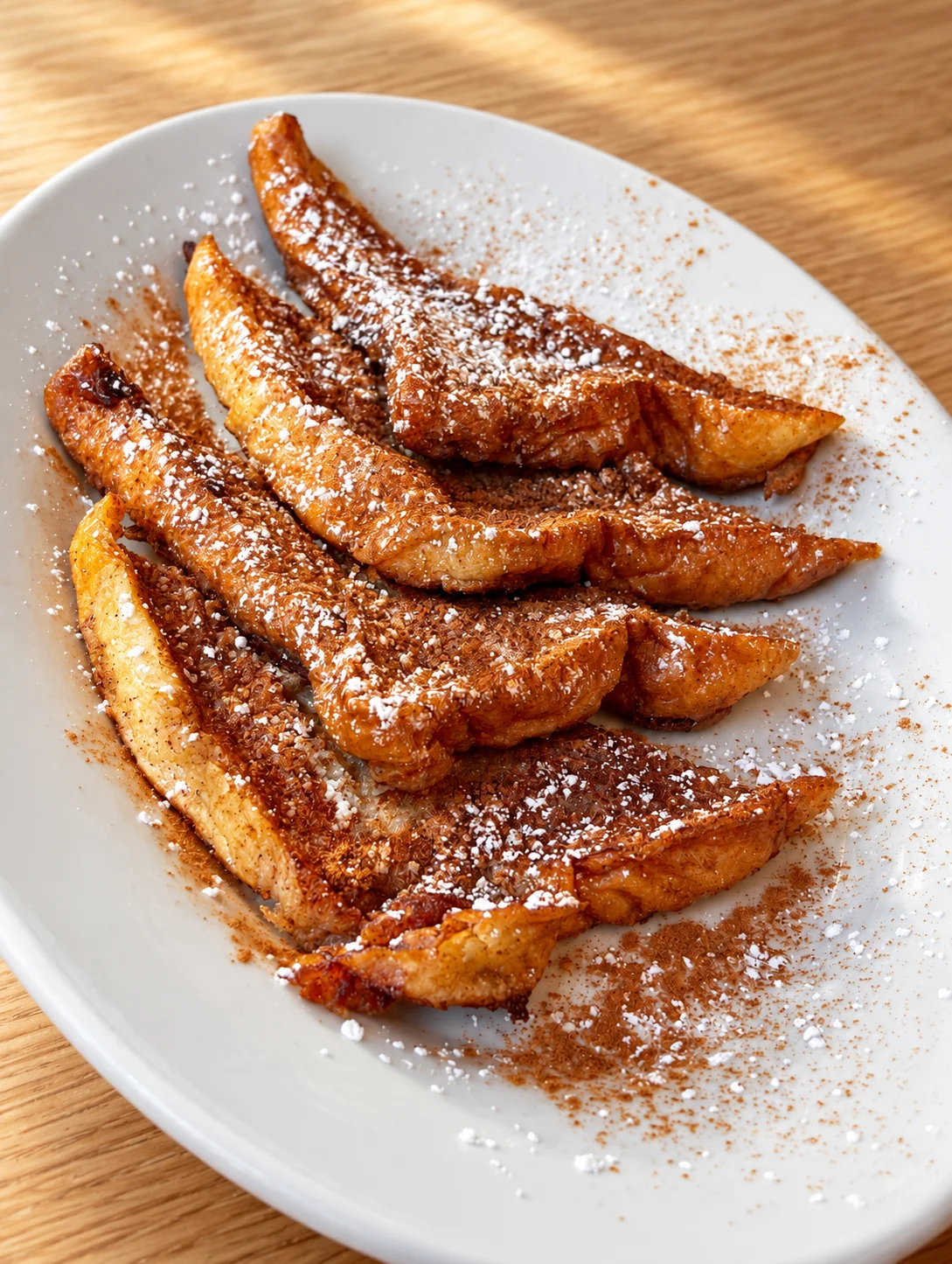 Cinnamon-dusted fried pastry wedges on a white plate