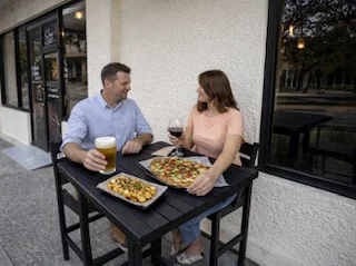 Couple enjoying pizza and drinks at an outdoor table