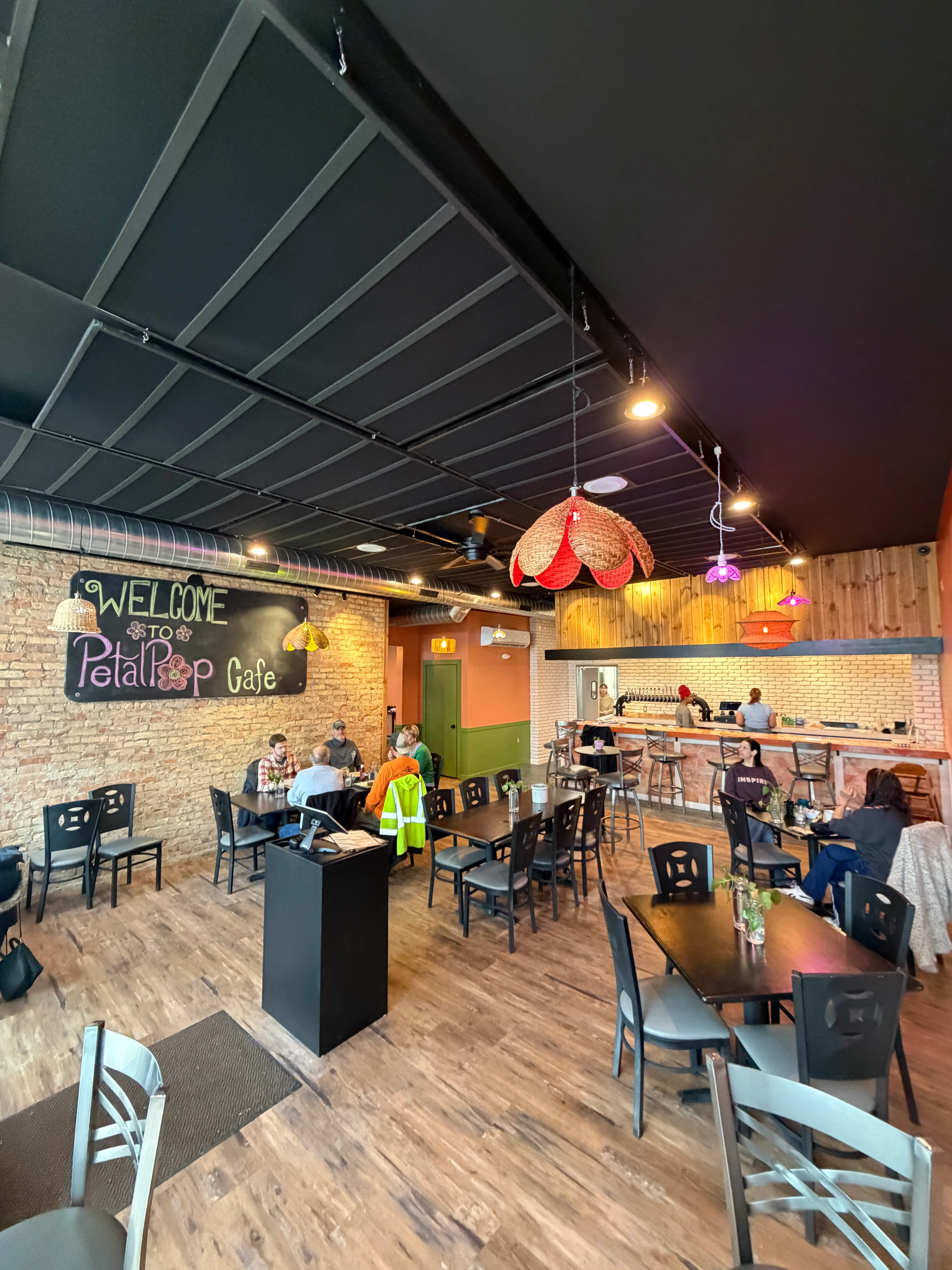 An empty indoor restaurant space with wooden floors, tables, and chairs, showcasing a welcoming ambiance.