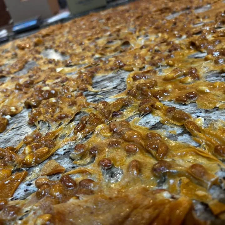 A textured surface of caramelized sugar and seeds, showcasing a golden-brown hue and crystallization.