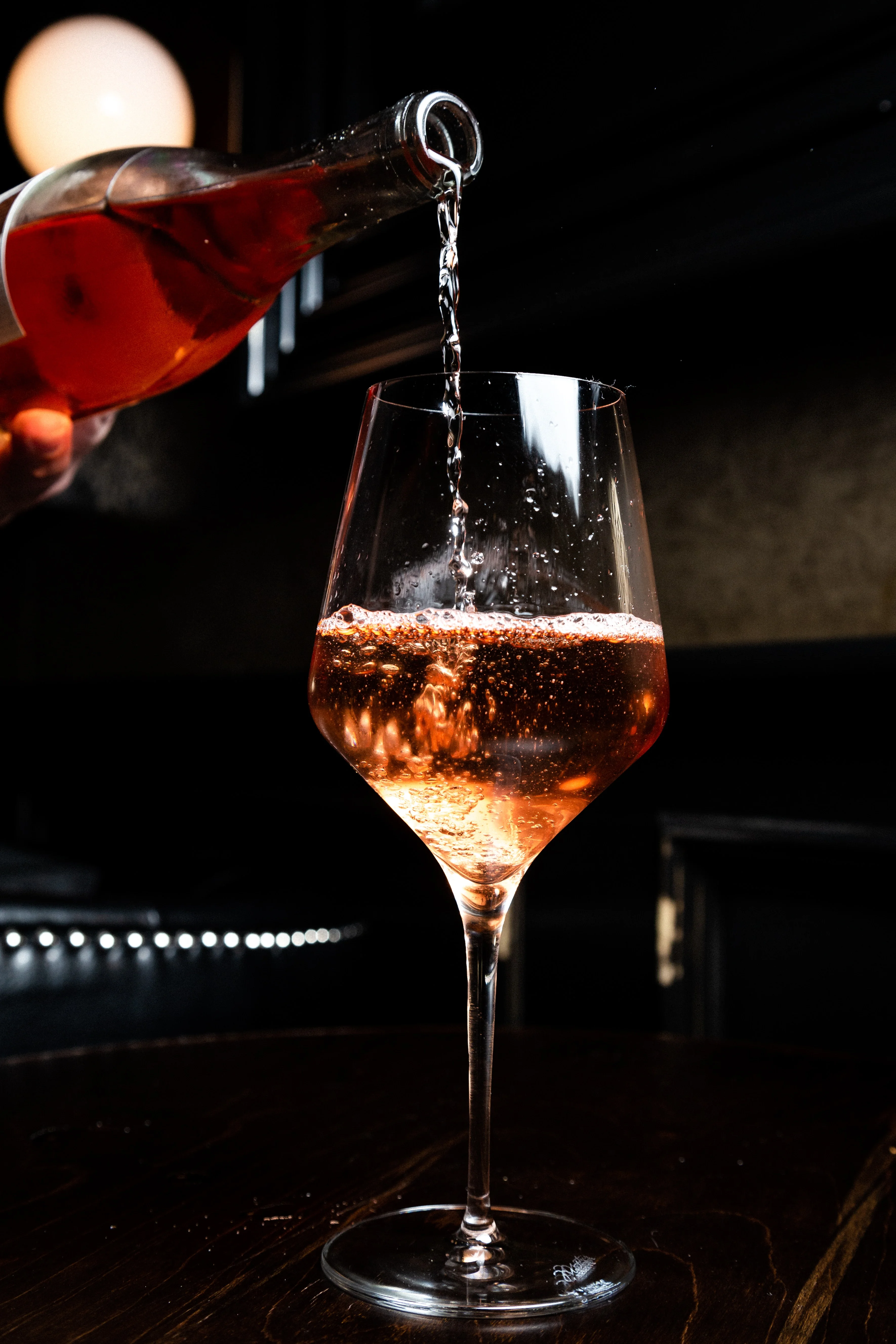 Pouring sparkling rosé into a wine glass