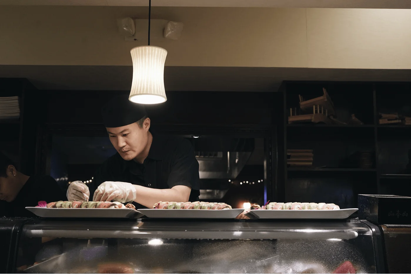 Sushi chef plating rolls behind the sushi bar at Mahzu East Windsor