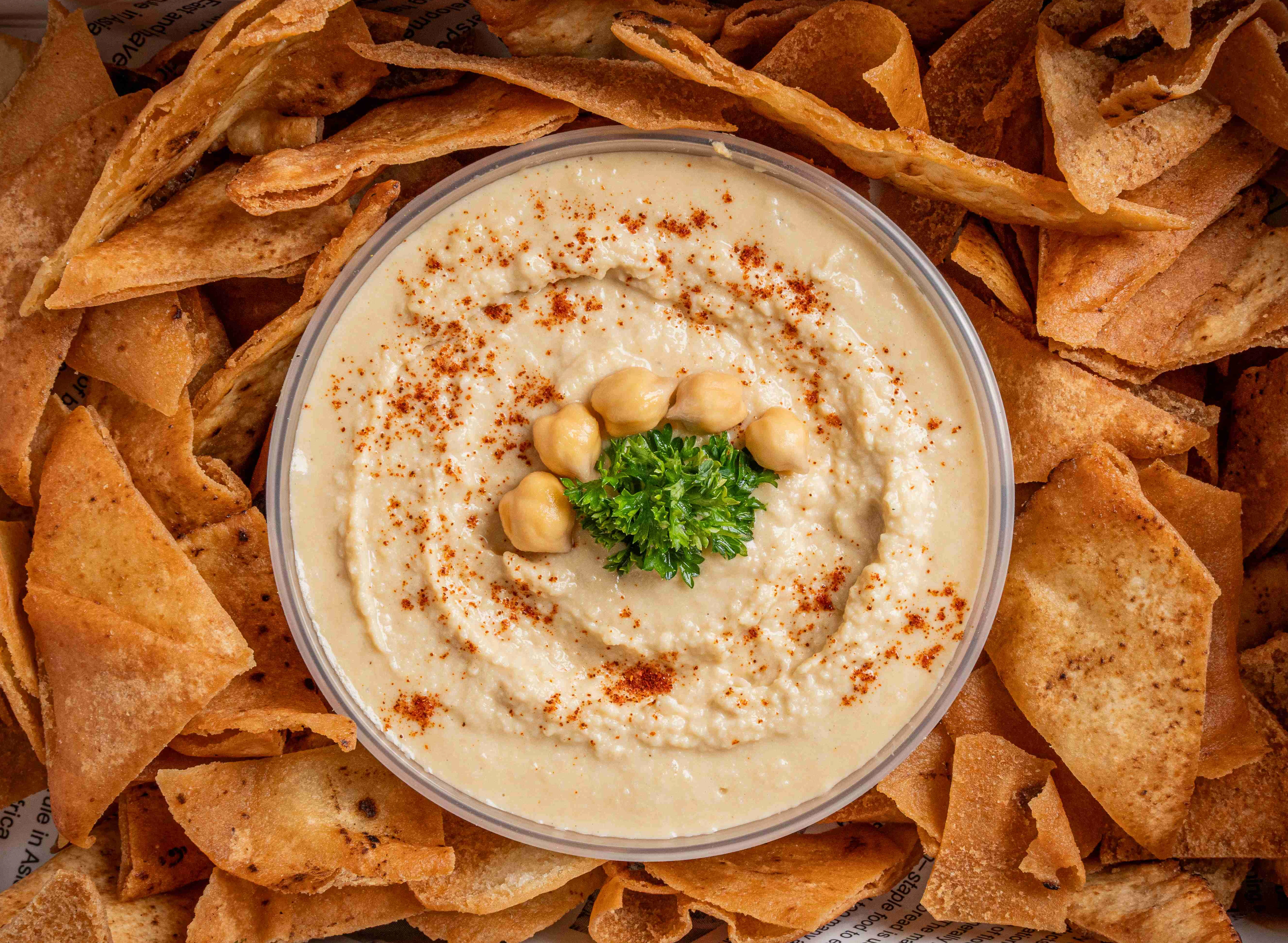 Hummus served with crispy pita chips in a decorative box.