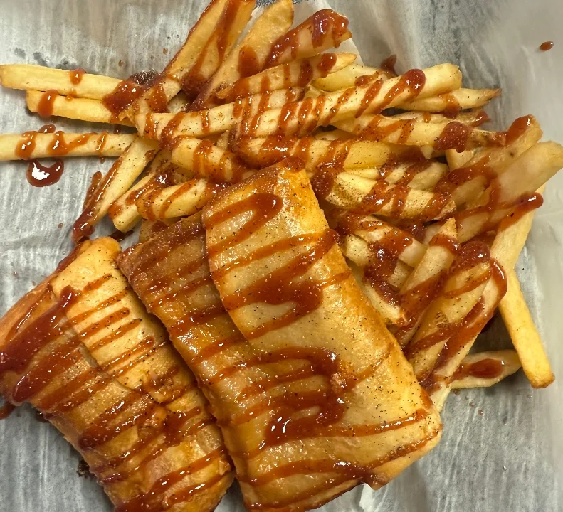 A serving of crispy fries drizzled with barbecue sauce, accompanied by a few pieces of a golden-brown dish.